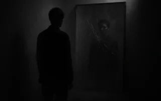 Человек стоит у разбитого зеркала